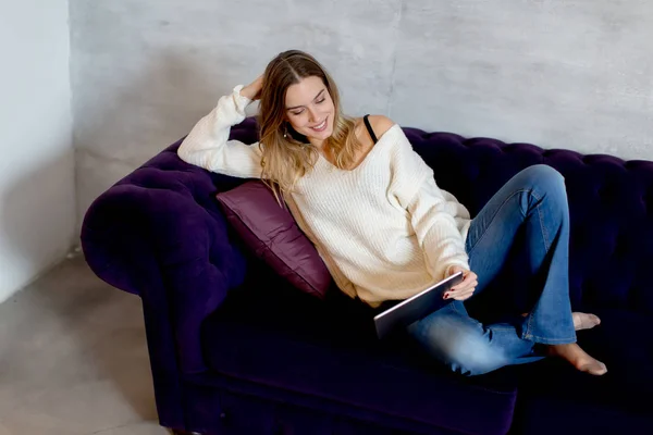 Mujer joven con la tableta en el sofá — Foto de Stock