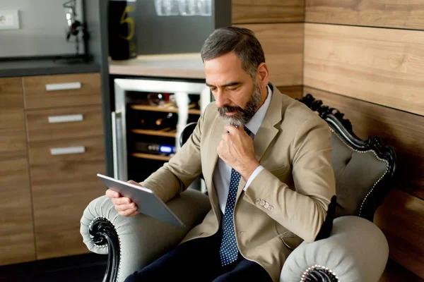 Senior-Geschäftsmann mit digitalem Tablet sitzt auf Sessel — Stockfoto