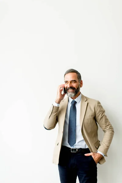 Bel homme d'affaires mature avec téléphone portable dans le bureau — Photo