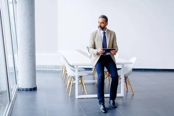 Schöner reifer Geschäftsmann mit digitalem Tablet im Büro — Stockfoto