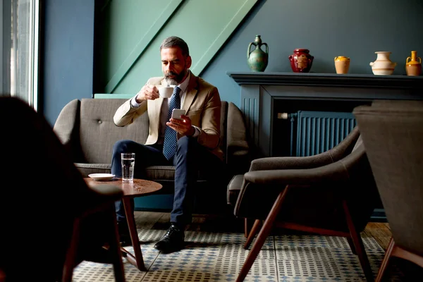 Όμορφος γενειοφόρος επιχειρηματίας πίνει καφέ και πραγματοποίηση τηλεφωνικής κλήσης — Φωτογραφία Αρχείου