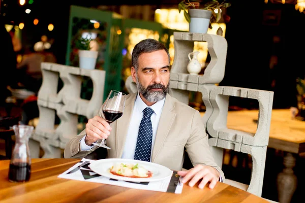 Όμορφος άνδρας πόσιμο κόκκινο κρασί κατά τη διάρκεια γεύματος — Φωτογραφία Αρχείου