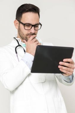 Beyaz duvar tarafından dijital tablet ile genç doktor