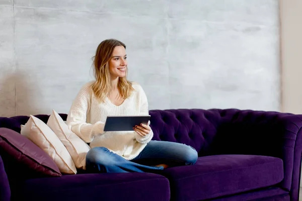 Jovem com tablet no sofá — Fotografia de Stock