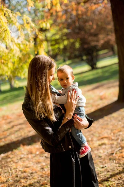 Padres jóvenes felices con bebé en el parque de otoño — Foto de Stock