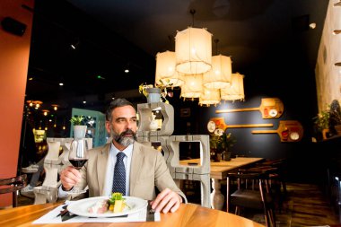 Öğle yemeği sırasında kırmızı şarap içme yakışıklı olgun adam