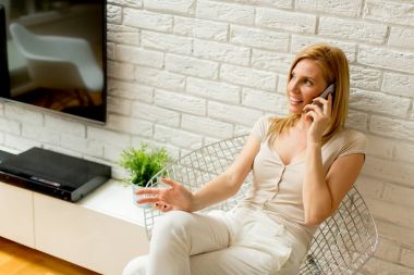 Oturma odasında ve cep telefonuyla genç kadın