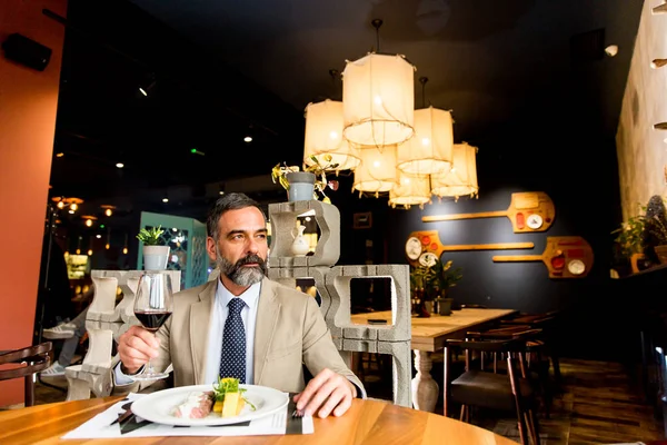 Öğle yemeği sırasında kırmızı şarap içme yakışıklı olgun adam