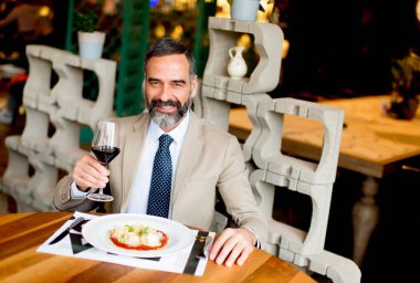 Öğle yemeği sırasında kırmızı şarap içme yakışıklı olgun adam