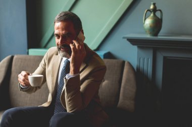 Kahve ve lobiye telefon görüşmesi yapma yakışıklı sakallı işadamı içecekler