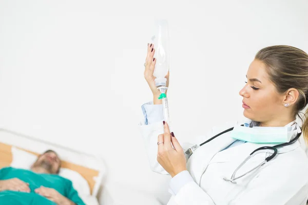 Female doctor prepares an injection while the patient is in bed — Stock Photo, Image