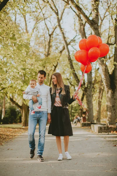 Feliz joven padres con bebé niño en otoño parque celebración de bal rojo — Foto de Stock