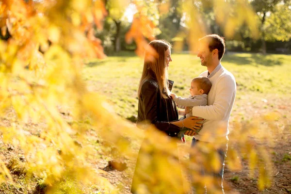 Padres jóvenes felices con bebé en el parque de otoño — Foto de Stock