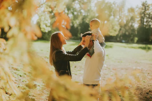 Felice giovane genitori con bambino nel parco autunnale — Foto Stock