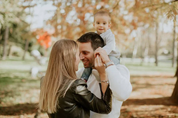 Padres jóvenes felices con bebé en el parque de otoño — Foto de Stock