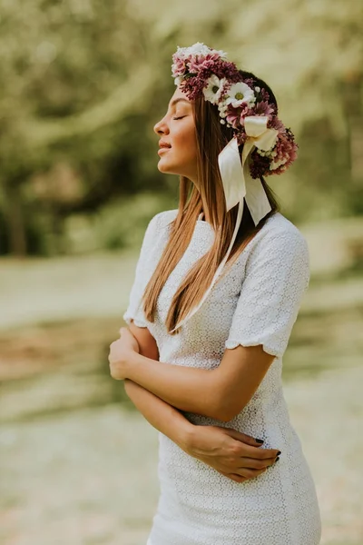 Portret van een jonge vrouw met krans van verse bloemen op hoofd — Stockfoto