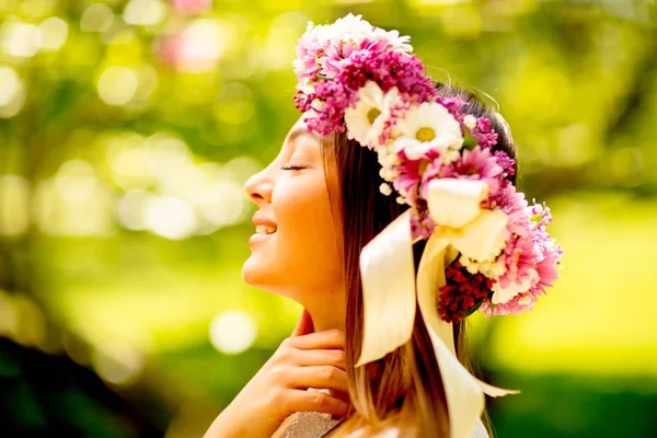 Portrait of young woman with wreath of fresh flowers on head — Stock Photo, Image