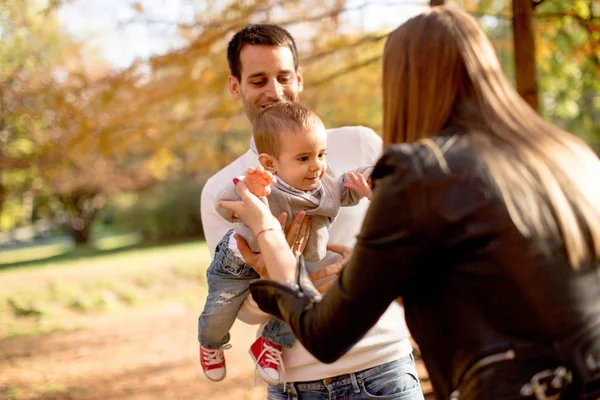 Padres jóvenes felices con bebé en el parque de otoño — Foto de Stock