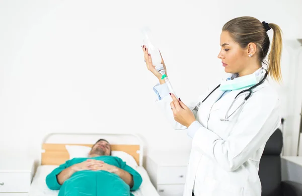 Vrouwelijke arts bereidt een injectie, terwijl de patiënt in bed — Stockfoto
