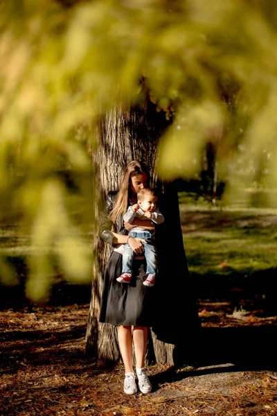 Young mother and baby boy in autumn park — Stock Photo, Image