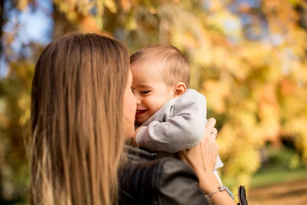 Jonge moeder en baby jongen in herfst park — Stockfoto