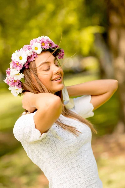 Portrait of young woman with wreath of fresh flowers on head — Stock Photo, Image