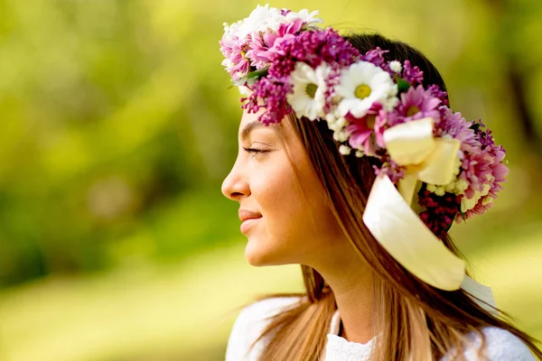 Portrait of young woman with wreath of fresh flowers on head — Stock Photo, Image