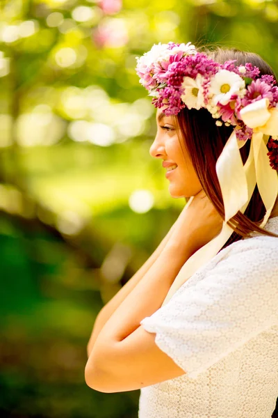 Portrait of young woman with wreath of fresh flowers on head — Stock Photo, Image