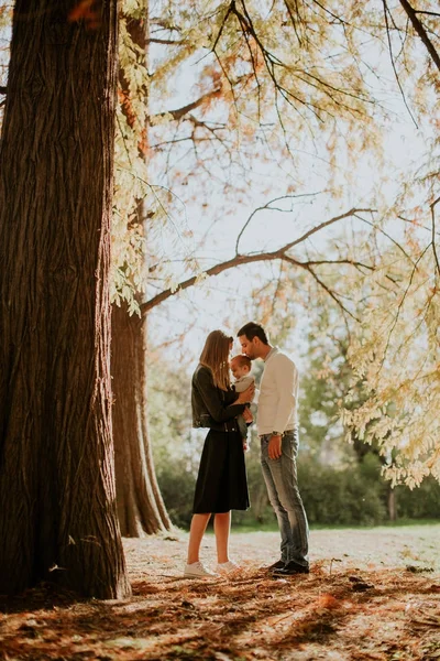 Felice giovane genitori con bambino nel parco autunnale — Foto Stock