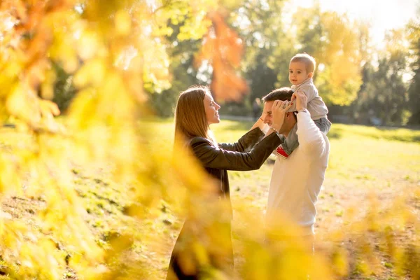 Happy young parents with baby boy in autumn park — Stock Photo, Image