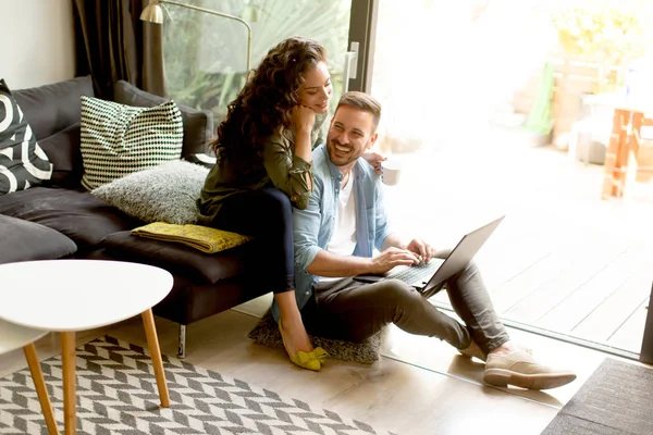 Casal jovem sentado no chão e usando notebook . — Fotografia de Stock