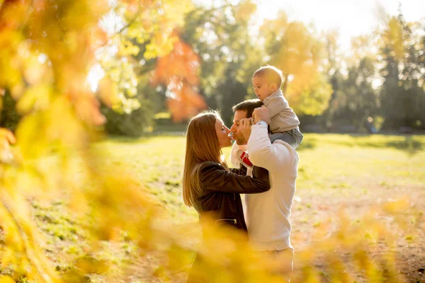Glückliche junge Eltern mit Baby im Herbstpark — Stockfoto