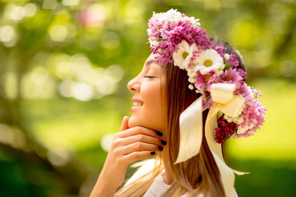 Portrait of young woman with wreath of fresh flowers on head — Stock Photo, Image