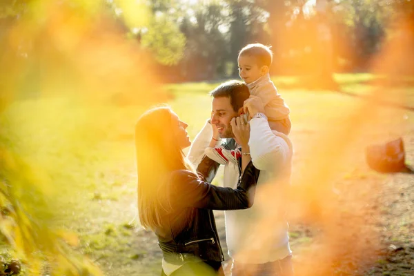 Счастливые молодые родители с мальчиком в осеннем парке — стоковое фото