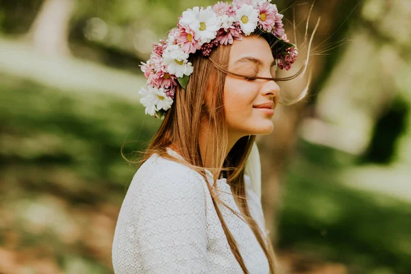 Portrait of young woman with wreath of fresh flowers on head — Stock Photo, Image