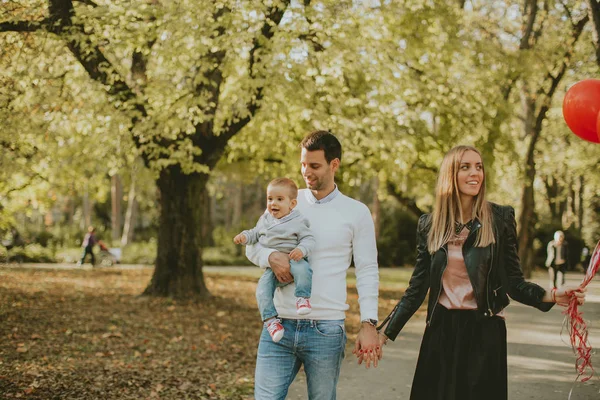 Feliz joven padres con bebé niño en otoño parque celebración de bal rojo — Foto de Stock