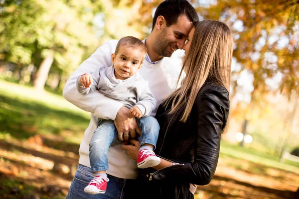 Happy young parents with baby boy in autumn park — Stock Photo, Image