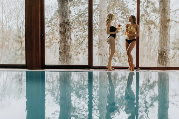 Mujeres jóvenes de pie con cócteles junto a la piscina —  Fotos de Stock