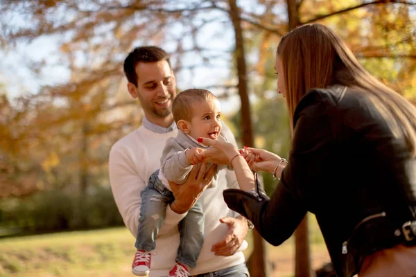 Padres jóvenes felices con bebé en el parque de otoño — Foto de Stock