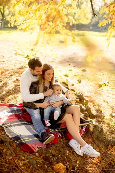 Sonbahar park yere oturan genç aile — Stok fotoğraf