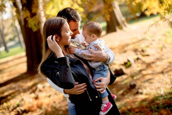 Jovens pais felizes com menino no parque de outono — Fotografia de Stock