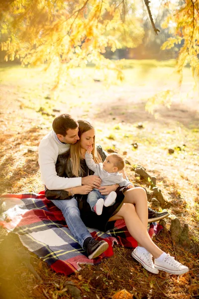 秋の公園で地面に座って若い家族で表示します — ストック写真