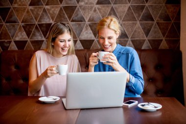 Cafe masa başına oturmuş dizüstü bilgisayar ile genç ve güzel kadınlar