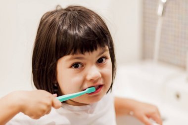 Küçük kız dişlerini fırçalıyor.