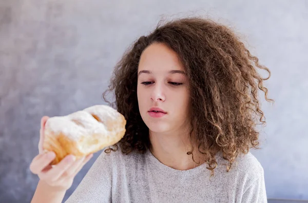 Cabelo encaracolado menina adolescente comer croissant — Fotografia de Stock