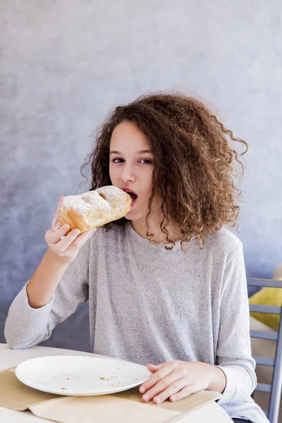 Cabelo encaracolado menina adolescente comer croissant — Fotografia de Stock