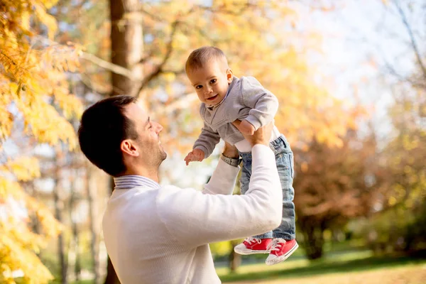 阳光明媚的日子 年轻的父亲和男婴在秋季公园玩耍 — 图库照片