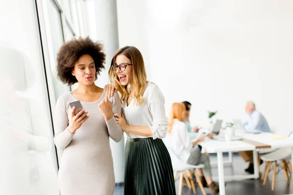 Junge Multiethnische Geschäftsfrauen Lächeln Während Andere Geschäftsleute Hintergrund Büro Arbeiten — Stockfoto