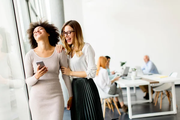 Jóvenes Empresarias Multirraciales Sonriendo Mientras Otros Empresarios Trabajan Segundo Plano —  Fotos de Stock