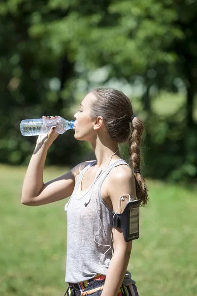 स्पोर्टि युवा महिला पानी पी रही — स्टॉक फ़ोटो, इमेज